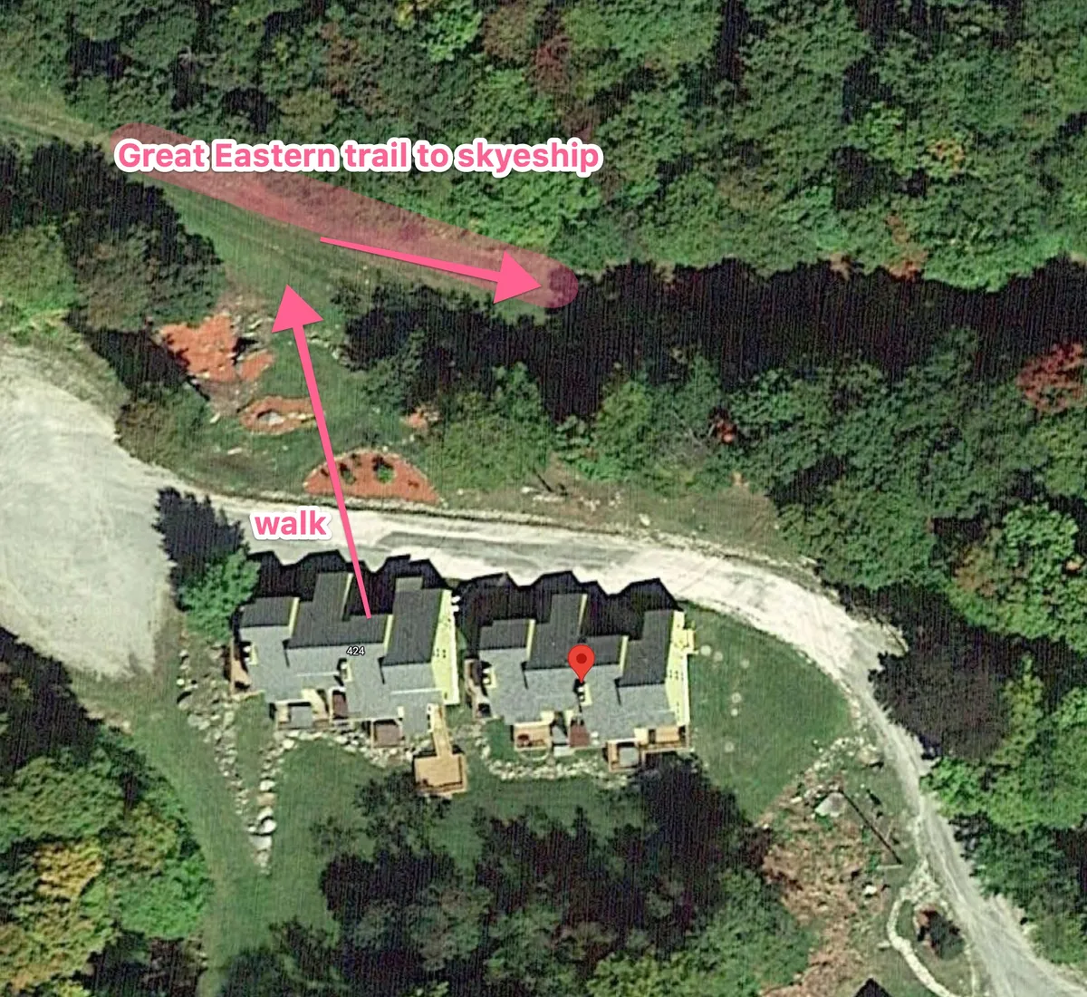 This image captures the famed Great Eastern trail with three houses situated alongside a walkway. The ground is snow-covered, and the houses are set against a natural, wooded backdrop, illustrating direct trail access and the proximity of homes to outdoor adventure.