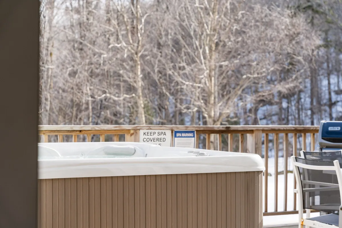 This exterior shot highlights a private wooden deck nestled among trees, with a hot tub as the main feature. The surrounding natural landscape provides a tranquil, secluded feel ideal for relaxation. The deck appears spacious enough for gatherings or quiet moments, with the hot tub positioned to maximize views and atmosphere.