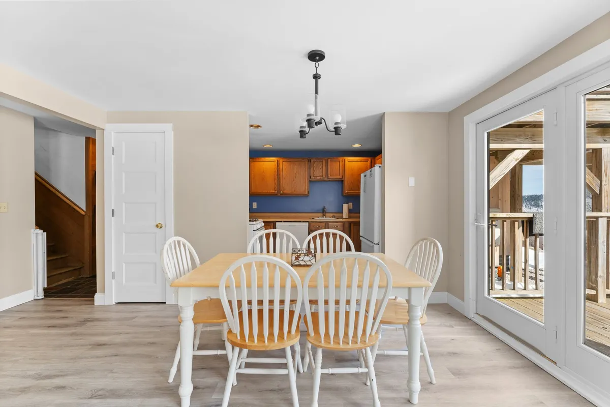 A cozy dining table is set adjacent to the kitchen area, with sliding glass doors providing natural light. The open-plan design allows for easy flow between the kitchen and dining spaces, reinforcing the communal, family-friendly environment.