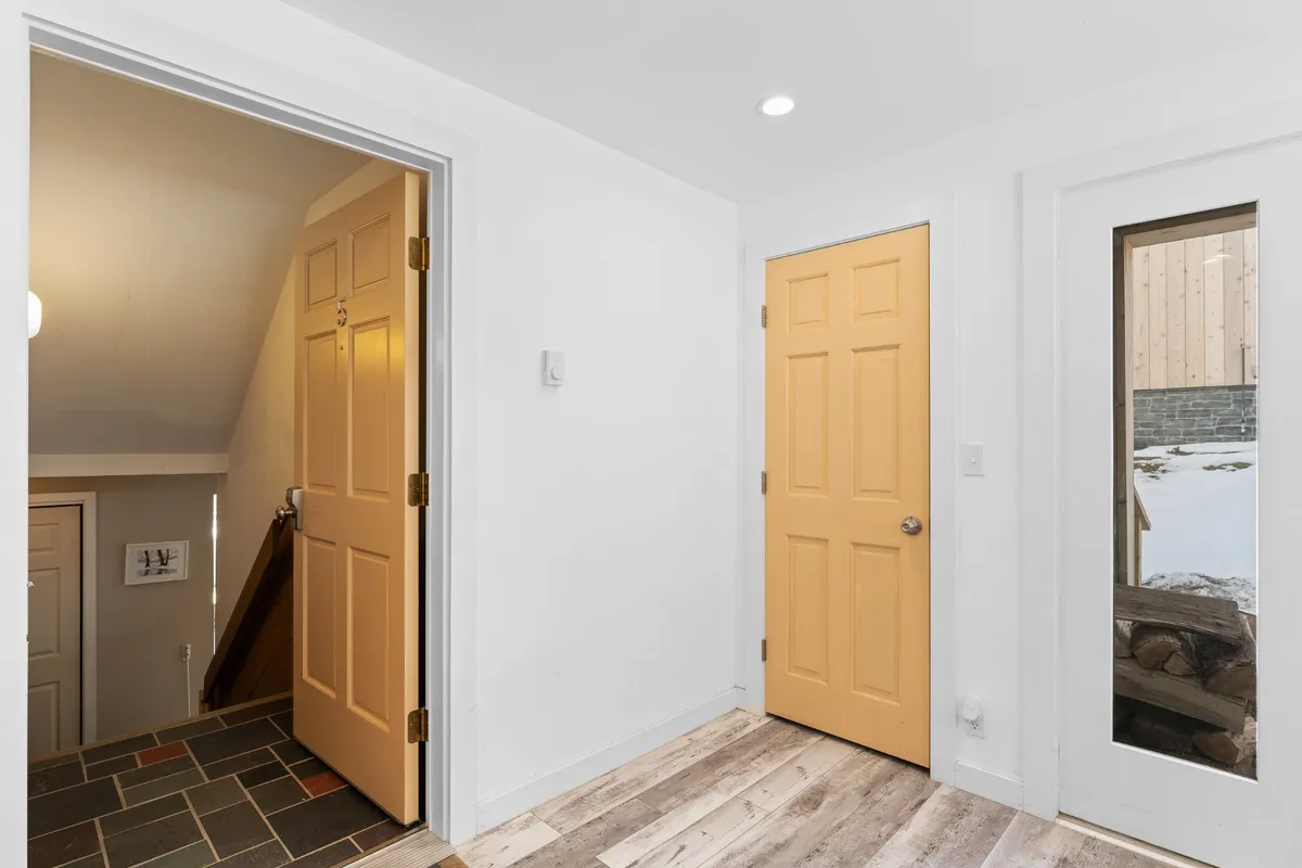 This inviting entryway features cheerful yellow doors, a staircase, and a window offering a glimpse outdoors. The transitional space is welcoming, signaling the beginning of an adventure in Killington—whether coming home from a day in the village or heading out to explore.